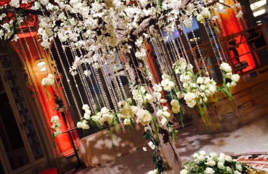 Artificial white blossom tree for hire, hung with crystal strands, above a bed of white roses on a mosaic floor