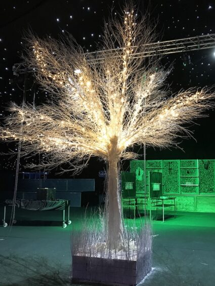 Artificial white tree for hire, covered in warm fairy lights in a dark marquee with a starry ceiling