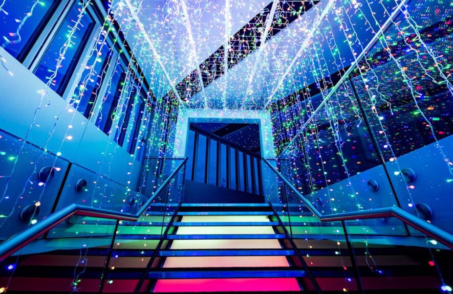 Curtains of multicolour fairy lights over a staircase with glowing coloured steps