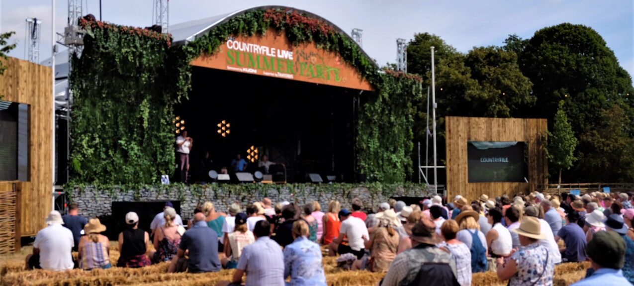 Artificial ivy walls for hire, framing the 'Countryfile Live Summer Party' stage, with spectators on straw bales