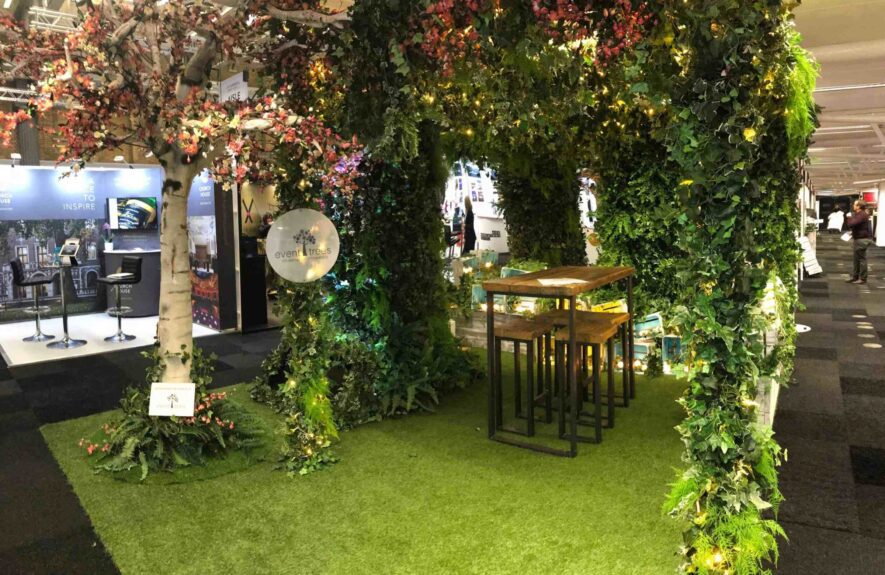 Artificial ivy arch and blossom tree for hire, installed over a high table and artificial grass at an exhibition