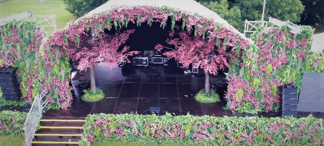 Artificial pink blossom trees for hire, placed on a domed festival stage framed by pink blossom and ivy walls