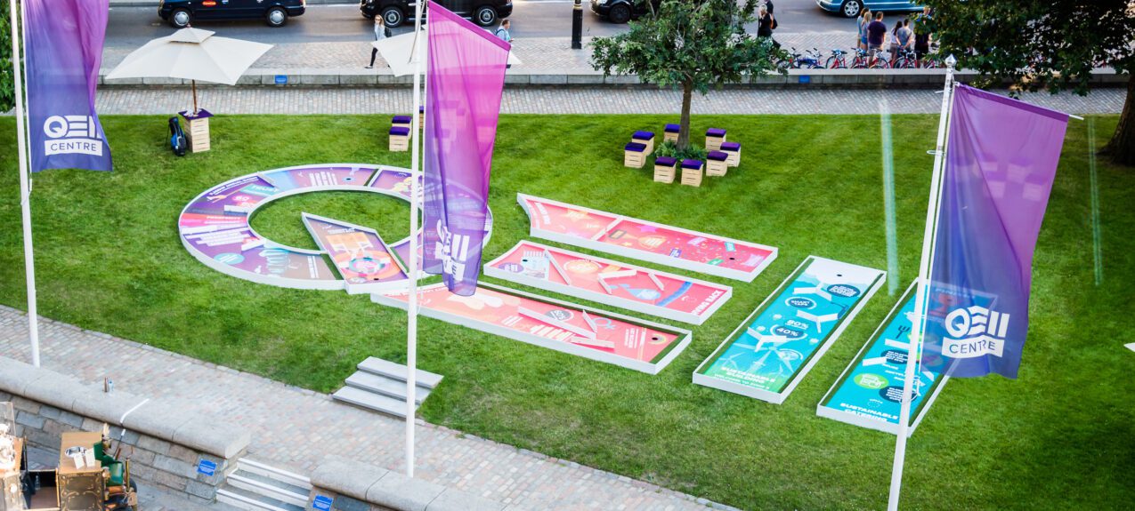 Aerial view of a crazy golf course on a lawn with QEII Centre flags and wooden box seats