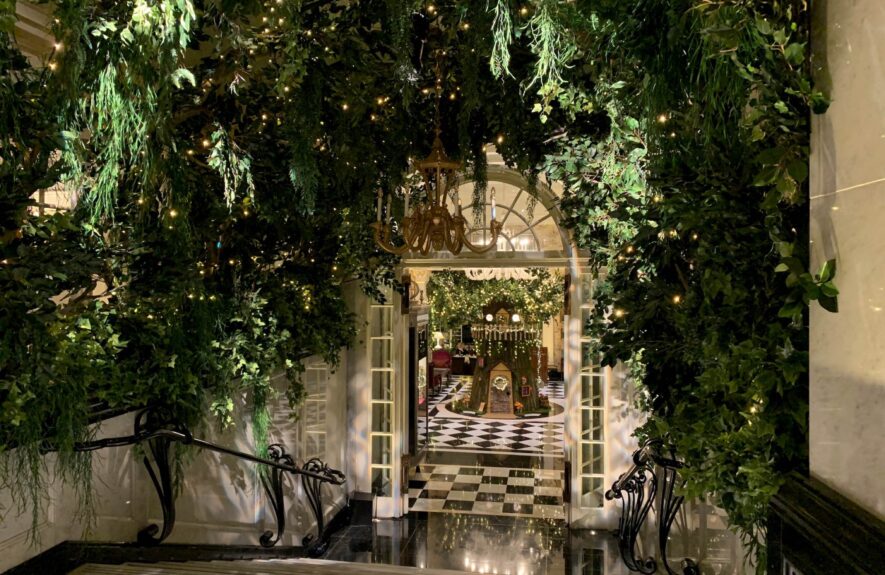 Artificial leafy foliage and trailing greenery for hire, with fairy lights over a Savoy Hotel passage and chandelier