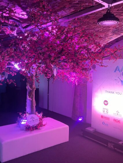 Artificial cherry blossom tree for hire under a brick vaulted ceiling, lit pink, beside an Event Odyssey backdrop