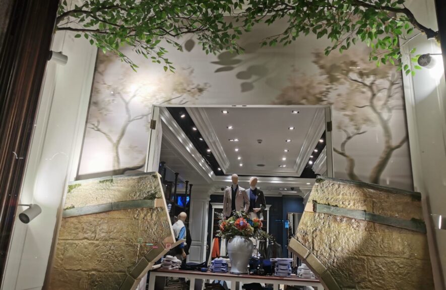 Artificial leafy branches for hire, spanning a boutique window display with stone-effect walls and a flower arrangement