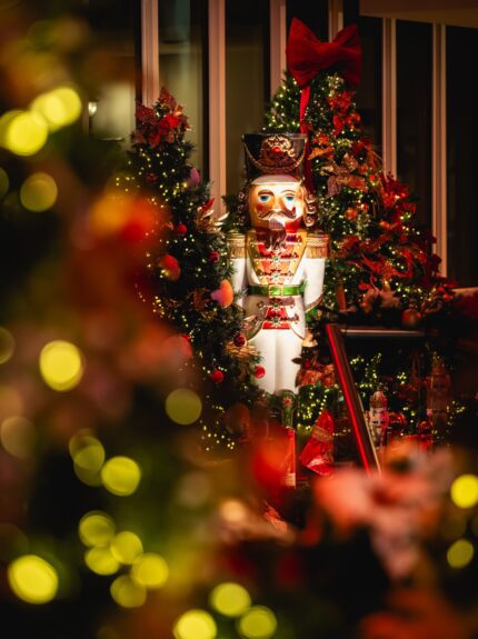 Giant nutcracker statue and decorated artificial Christmas trees for hire, glowing with fairy lights at a Christmas party