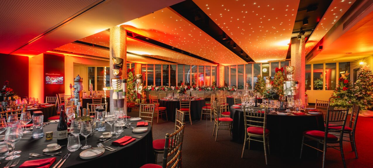 Decorated artificial Christmas trees and nutcracker statues for hire, in a starlit-ceiling party room with red chairs