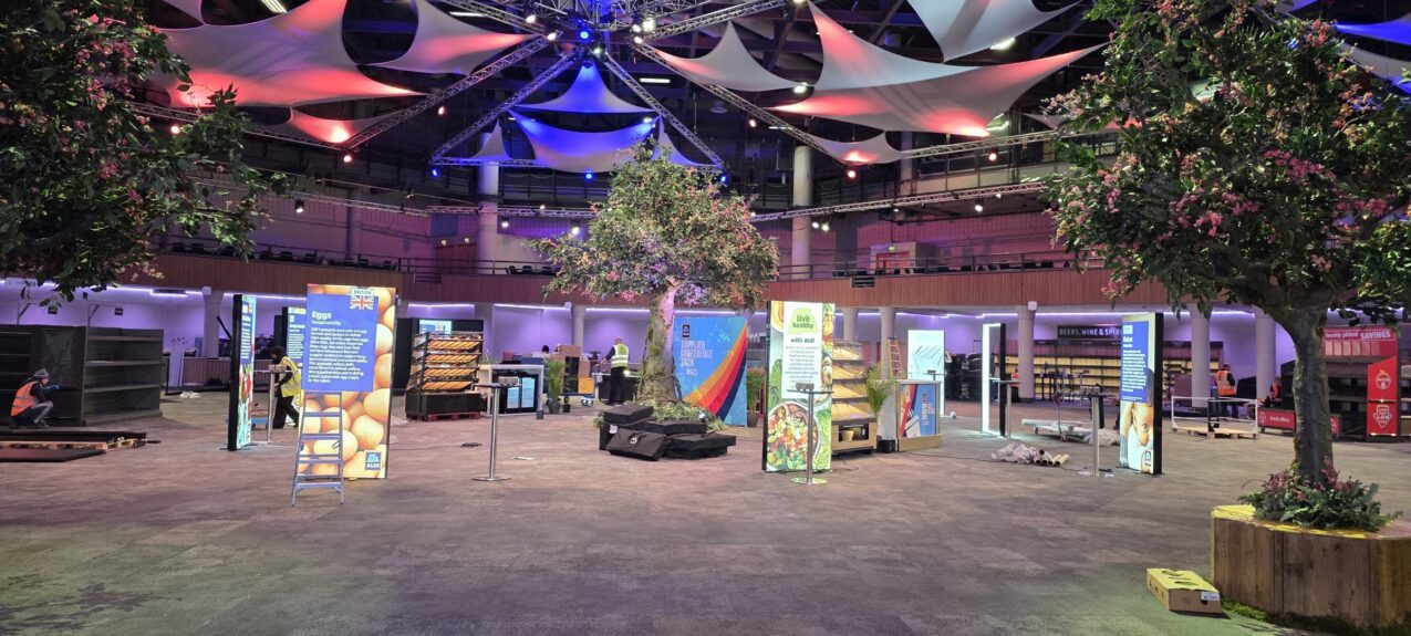 Artificial blossom trees for hire, placed around exhibition stands in a large hall with coloured ceiling sails