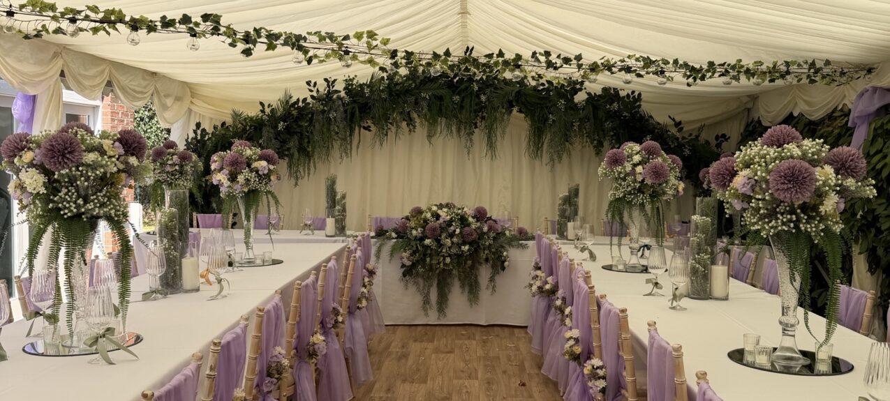 Artificial ivy garlands for hire, hung across a wedding marquee ceiling, with an ivy-draped backdrop behind the top table