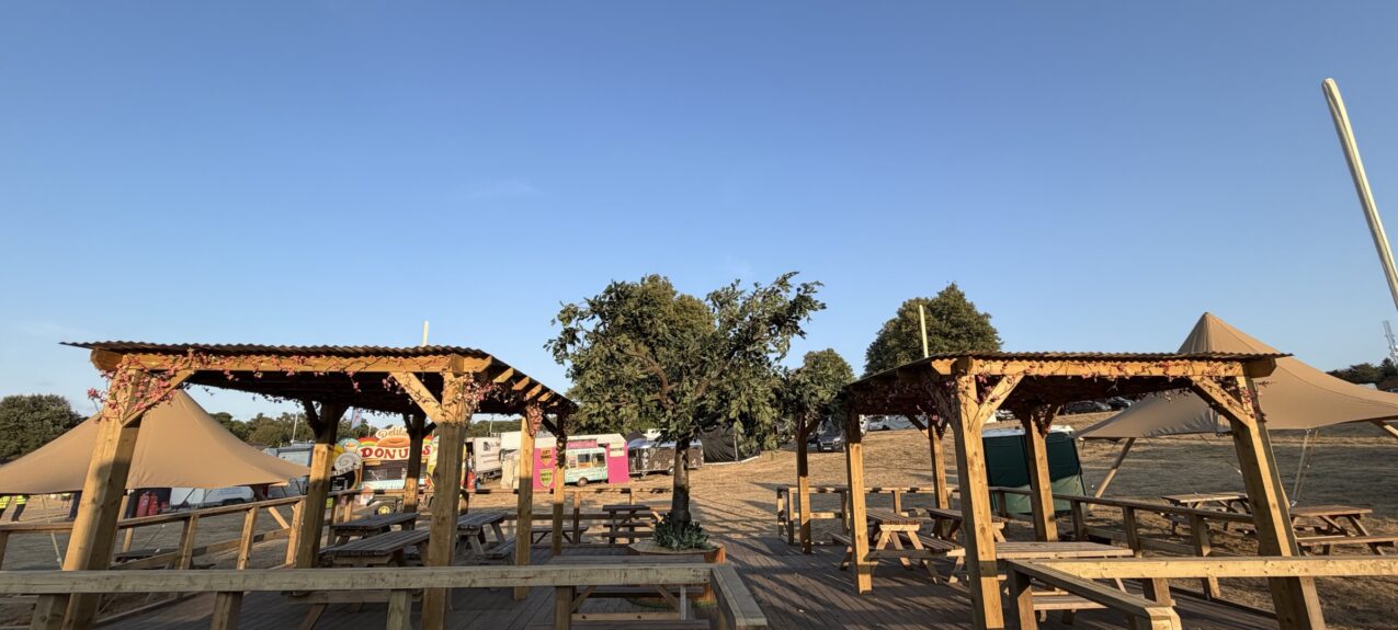 Artificial cherry blossom garlands for hire, wound round wooden pergolas over festival decking and picnic benches